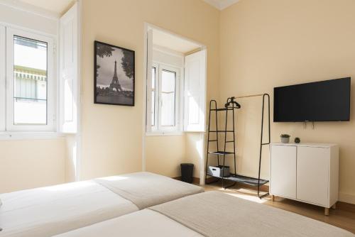 a bedroom with a bed and a flat screen tv at City Rooms Guest House by HD in Faro