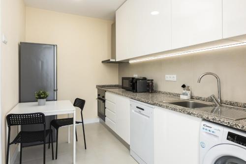 a kitchen with a sink and a table with chairs at City Rooms Guest House by HD in Faro