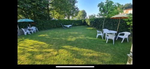 a yard with white chairs and tables and umbrellas at B&B Maison Saint Tropez Eindhoven in Eindhoven