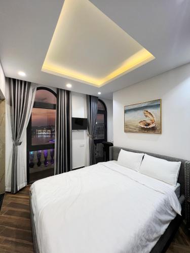a bedroom with a large white bed and a window at Legacy Hotel - Grand World Phú Quốc in Phu Quoc