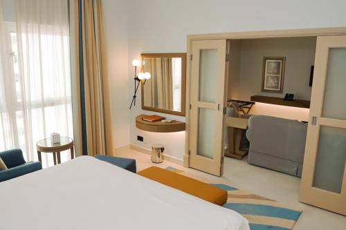 a hotel room with a bed and a mirror at Sheraton Khalidiya Hotel in Abu Dhabi