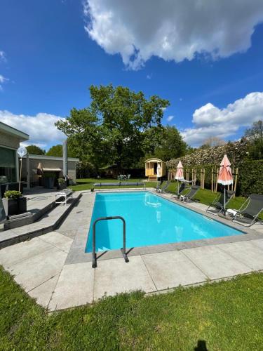 a swimming pool in a yard with chairs around it at B&B Maison Saint Tropez Eindhoven in Eindhoven
