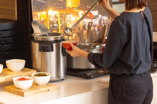a woman standing in a kitchen preparing food at ANA Crowne Plaza Fukuoka by IHG in Fukuoka
