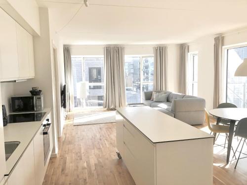 eine Küche und ein Wohnzimmer mit einem Sofa und einem Tisch in der Unterkunft Fantastic 3-bed w balcony in Ørestad in Kopenhagen