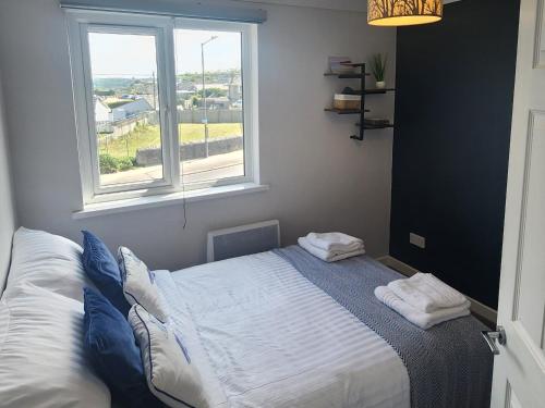 a bedroom with a bed with two pillows and a window at Top Location Perranporth Apartment in Perranporth