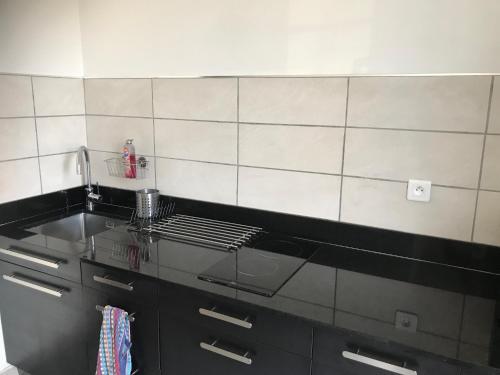 - une cuisine avec un comptoir en verre et un évier dans l'établissement Studio cosy proche de Paris, à Ermont