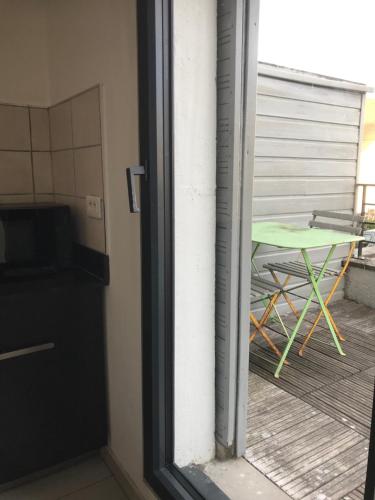 une porte menant à un balcon avec une table verte dans l'établissement Studio cosy proche de Paris, à Ermont