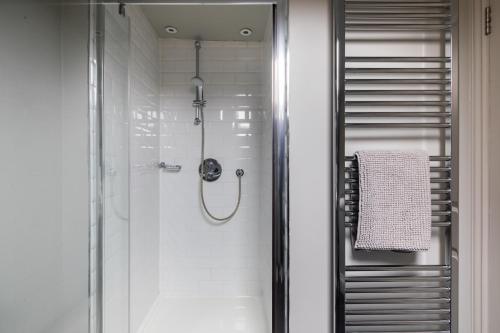 a shower with a glass door in a bathroom at Homely Parkside 2-Bed Apartment in Primrose Hill in London