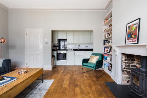 a living room with a fireplace and a green chair at Homely Parkside 2-Bed Apartment in Primrose Hill in London