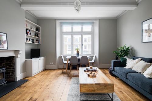 a living room with a blue couch and a table at Homely Parkside 2-Bed Apartment in Primrose Hill in London