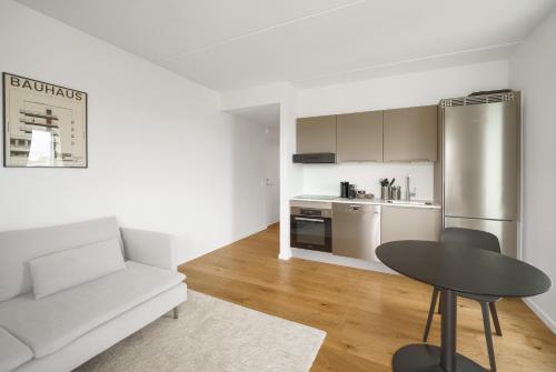 Top-class 1-bedroom apartment in Odense في أودنسه: غرفة معيشة بيضاء مع أريكة بيضاء وطاولة