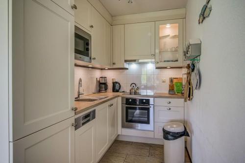 a kitchen with white cabinets and a sink and a stove at Appartement Regina - Residence Juliana Julianadorp aan Zee in Julianadorp