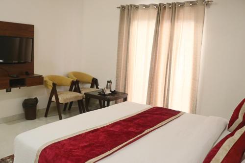 a bedroom with a bed and a table and a television at Guru Kripa sadan in Vrindāvan