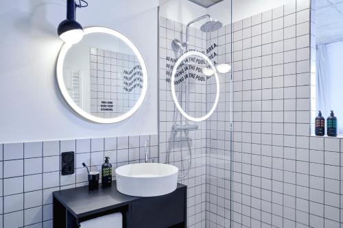 a white tiled bathroom with a sink and two mirrors at STAYERY Berlin Friedrichshain in Berlin