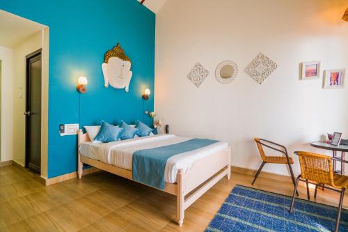 1 dormitorio con cama y pared azul en Sunfun Beach House en Kannur
