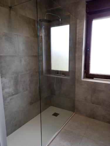 a shower with a glass door and a window at CASA FREDO in Cóbreces