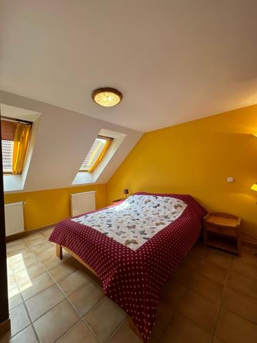 Un dormitorio con una cama roja en una pared amarilla en Apartment Roman villa, en Hévíz
