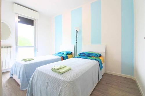 2 Betten in einem Zimmer mit blauen und weißen Streifen in der Unterkunft Holiday in Caorle