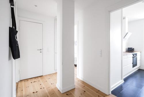 a white kitchen with white cabinets and a wooden floor at 2-BR apartment with a balcony in Charlottenlund - 192 in Charlottenlund