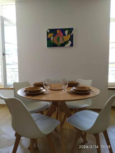 - une table en bois avec des chaises, des assiettes et des verres à vin dans l'établissement Grand T2 de charme, confort 3*, face aux Thermes., à La Bourboule