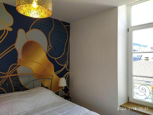 une chambre avec un lit avec un tableau sur le mur dans l'établissement Grand T2 de charme, confort 3*, face aux Thermes., à La Bourboule