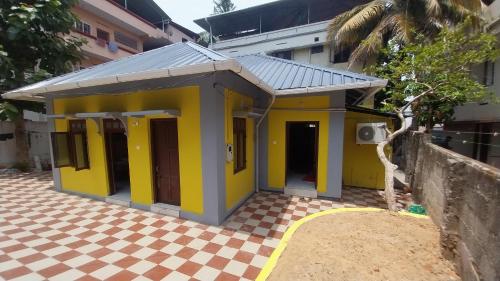 a small yellow house with a checkered floor at Hostel Gandhi Thiruvananthapuram in Trivandrum