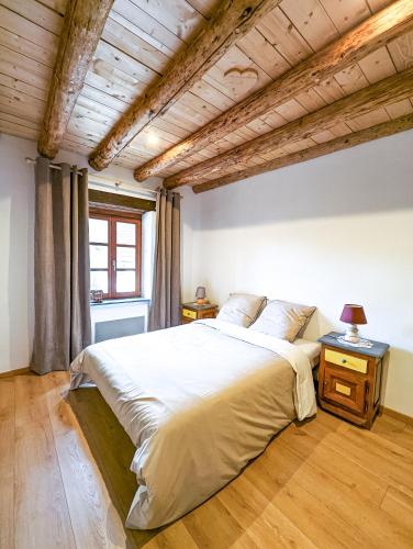 une chambre avec un grand lit avec un plafond en bois dans l'établissement La Fermette vosgienne de la Goutte, à Steige