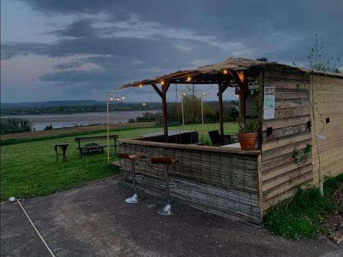 a bar with an umbrella and stools in front at Forest Glamping Retreat in Blakeney