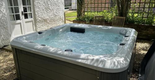 una bañera de hidromasaje en el patio trasero de una casa en April Cottage, luxurious accommodation for coast and forest with pool & hot tub, en Hordle