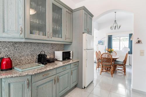 a kitchen with blue cabinets and a table with chairs at Villa Asossa with Private pool & Sea view in Dhaskalión