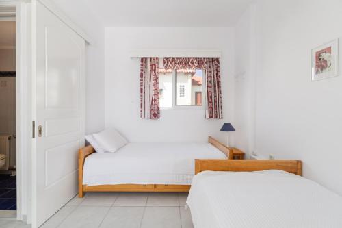 a white bedroom with a bed and a window at Villa Asossa with Private pool & Sea view in Dhaskalión