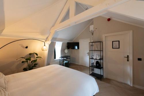 Stadsherberg de Poshoorn في ماستريخت: غرفة نوم مع سرير أبيض كبير في العلية