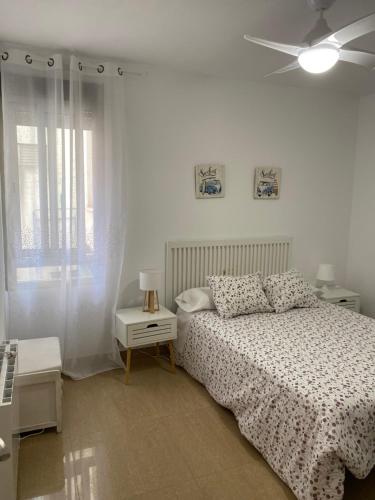 a white bedroom with a bed and a ceiling fan at Apartamento San Vicente in Villar del Arzobispo