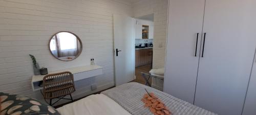 Dormitorio pequeño con cama y espejo en Holiday Portfolio Da Gama Bay, en St Helena Bay