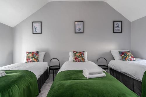 a room with three beds with green sheets at Kenny's Cottage in Kilkenny