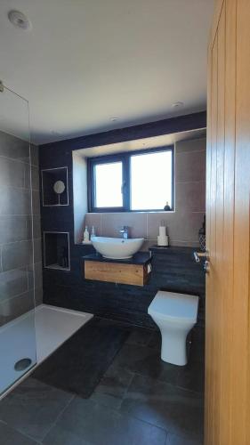 a bathroom with a sink and a toilet and a window at Surfers Lodge - Rest Bay, Porthcawl in Porthcawl