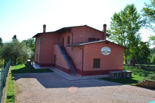 un pequeño edificio rojo con una escalera que conduce a él en La Bettola Tavern Rooms & Restaurant en Montopoli in Val dʼArno