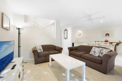 a living room with two couches and a tv at Cuttlefish Cove in Coffs Harbour