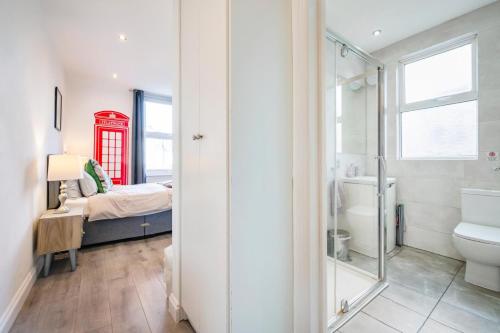 baño con cama y cabina de teléfono roja en City studios london en Londres