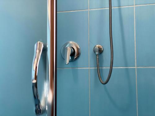a blue shower door with a shower head at Northgate Apart-Villa in Shkodër
