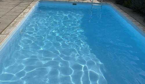 una piscina de agua azul en un patio en April Cottage, luxurious accommodation for coast and forest with pool & hot tub, en Hordle