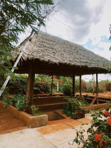 een paviljoen met een rieten dak in een tuin bij Vineyard Retreat Voi in Voi