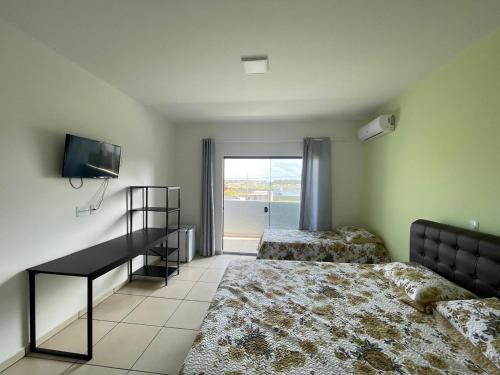 um quarto com 2 camas, uma televisão e uma janela em Pousada Barra Coast em Barra Velha