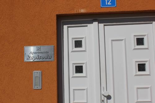 een witte deur met een bord ervoor bij Apartments Kapisoda in Cetinje