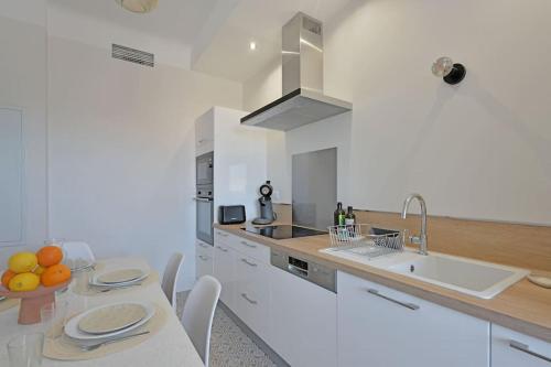 - une cuisine blanche avec une table et un évier dans l'établissement Une Nuit d'été - Vue Palais des Papes - Clim - Wi-Fi - Double terrasse - Parking gratuit, à Avignon