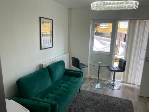 sala de estar con sofá verde y 2 sillas en The NEW! 1 Bedroom London House with Garden and Lawn en Londres