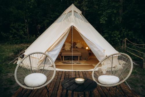 two chairs and a tent with a bed in it at Glamping U Lesa in Rychnov nad Kněžnou