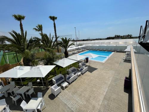 - une piscine extérieure avec des tables et des chaises blanches dans l'établissement Pandora B&B, à Porto Cesareo