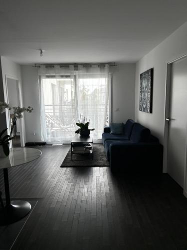un salon avec un canapé bleu et une table dans l'établissement Modern appartement, à Nogent-sur-Marne