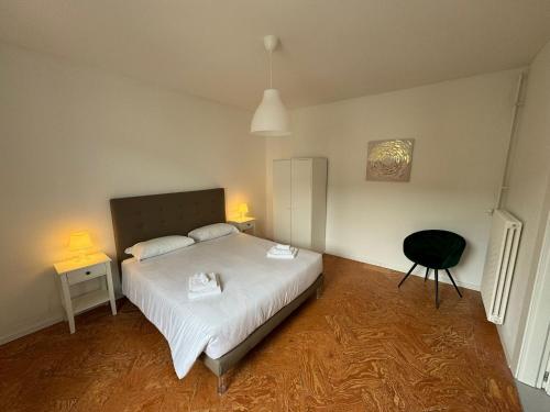 a bedroom with a white bed and a black chair at Smart Living Swiss in Chiasso